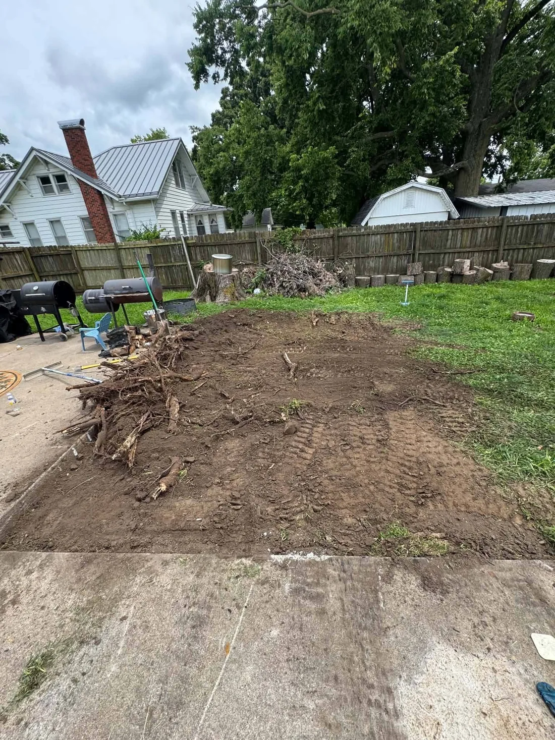 Before photo of a plain backyard patio area before gravel sitting area work