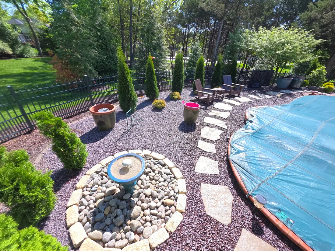 Poolside hardscape with gravel, plants, and stepping stones around a fire feature