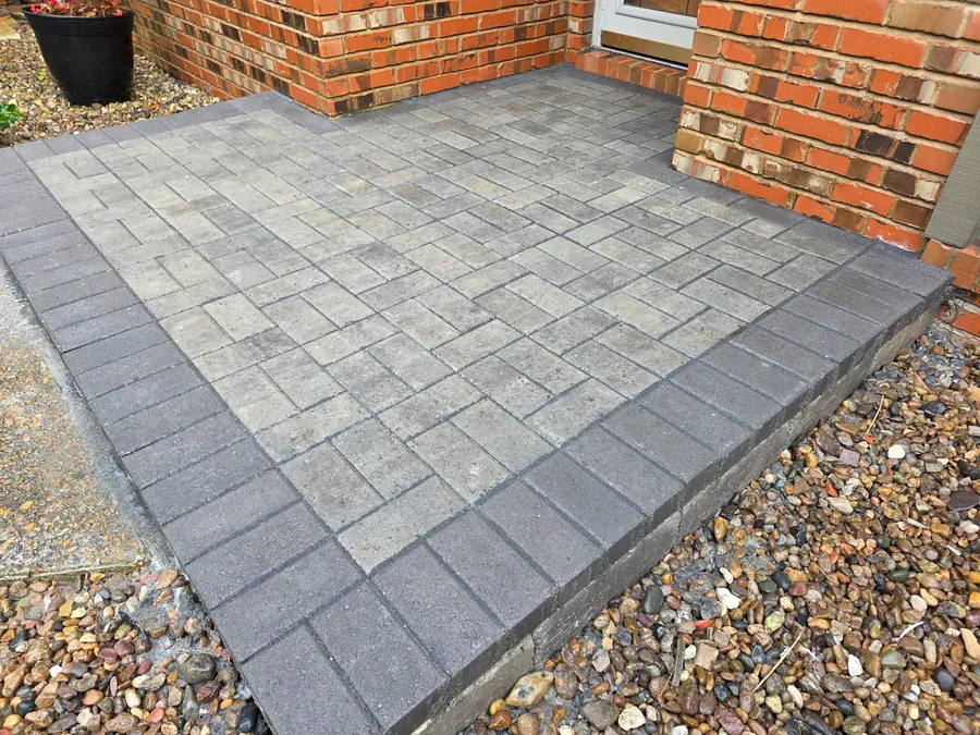 Gray paver patio section installed beside a brick entry
