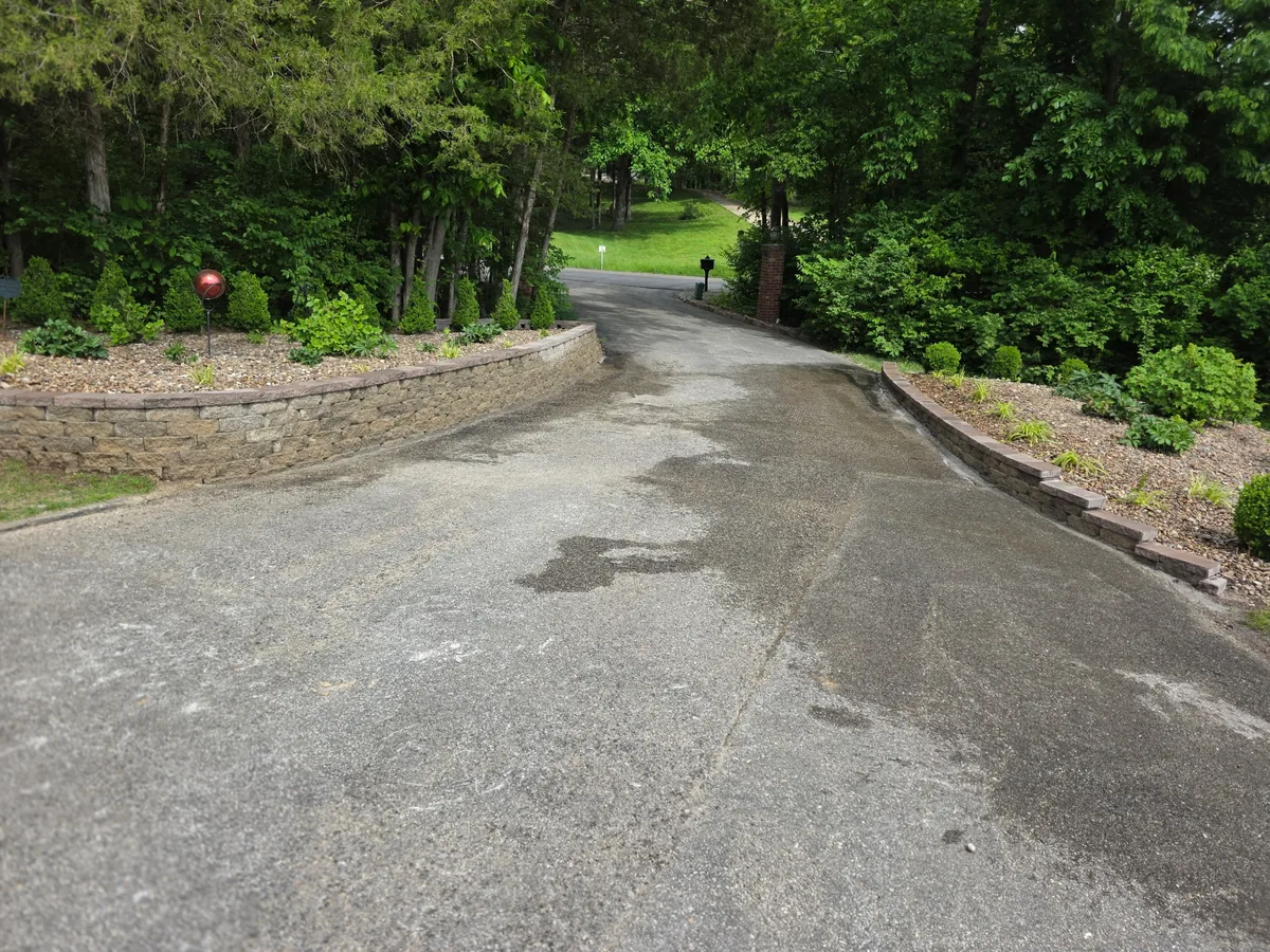 After photo of a driveway edge with cleaned rock beds, block edging, and planted areas